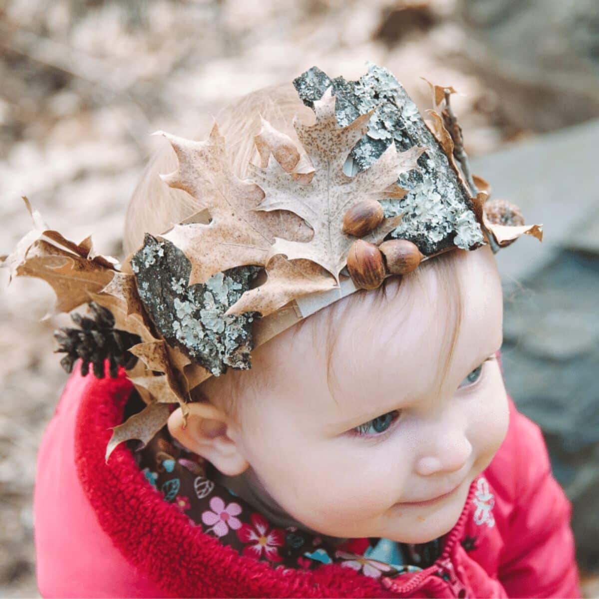 A child wearing a DIY nature crown with bark, leaves, and acorns glued onto it.