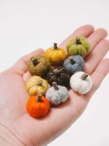 Mini felt ball pumpkins with tiny stems made from pieces of sticks.